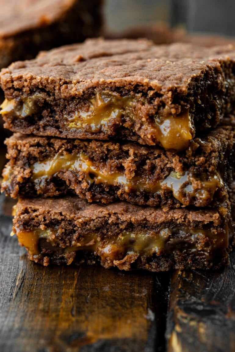 a stack of three chocolatey brownies with a buttery caramel layer