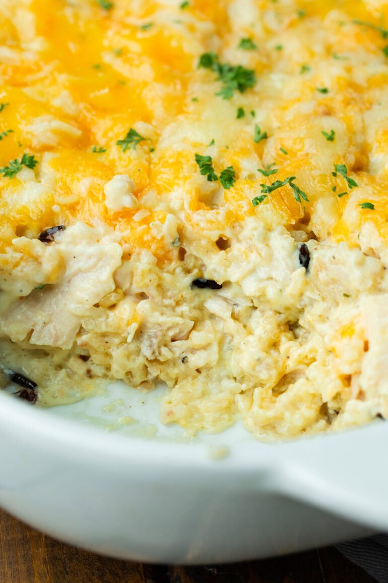 a photo of a chicken and rice casserole in a casserole dish with scoops of the casserole removed
