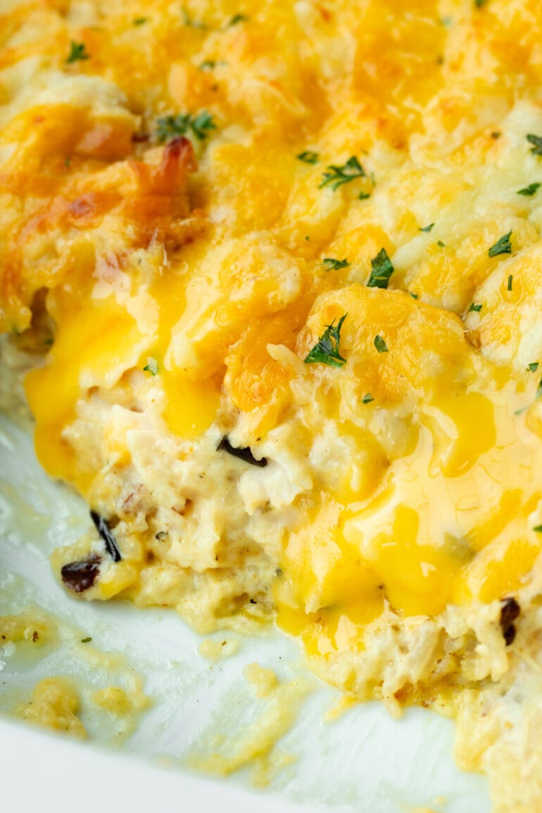 a photo of creamy chicken and rice casserole in a baking dish topped with melted colby jack cheese.
