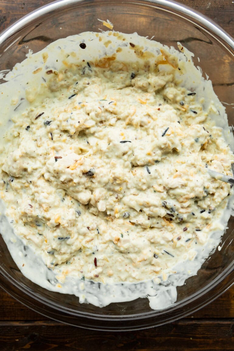 a photo of the ingredients for cheesy chicken and rice casserole in a large bowl ready to be poured into the baking dish