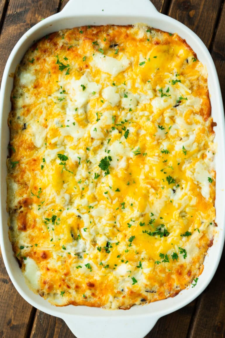 a photo of a baking dish full of chicken and rice casserole topped with melted cheese