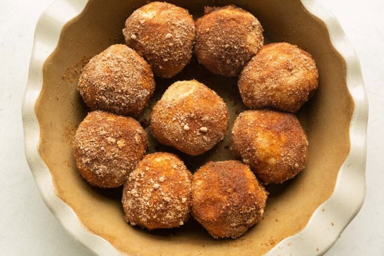 Cinnamon sugar coated dough balls arranged in a pie plate before rising and baking