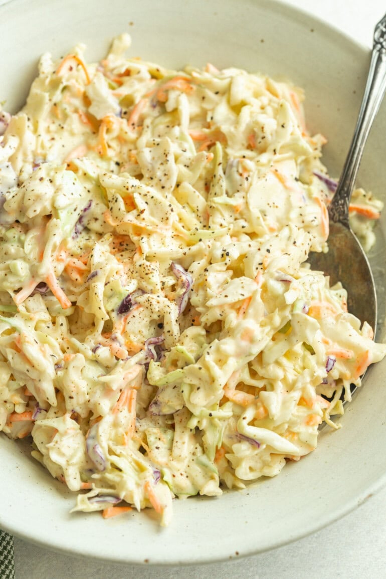 A heaping bowl of creamy homemade coleslaw made with crisp green cabbage, shredded carrots, and tangy mayo dressing.