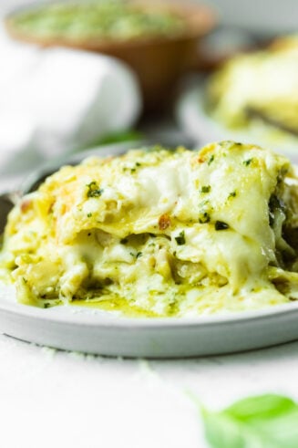 a photo of a piece of pesto chicken lasagna sitting on a white plate