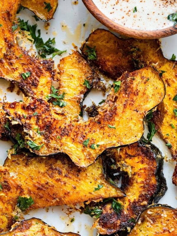a photo of several slices of roasted acorn squash with fresh parsley sprinkled on top