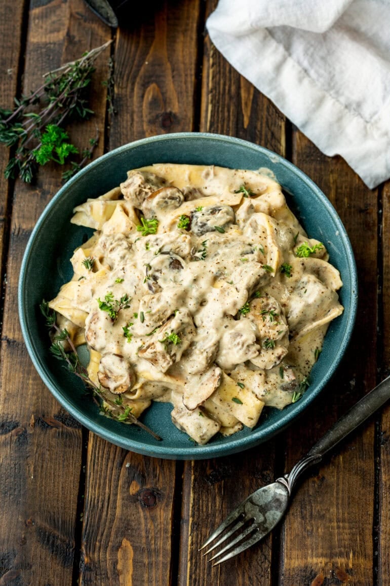 A photo of a bowl filled with beef stroganoff and topped with fresh herbs