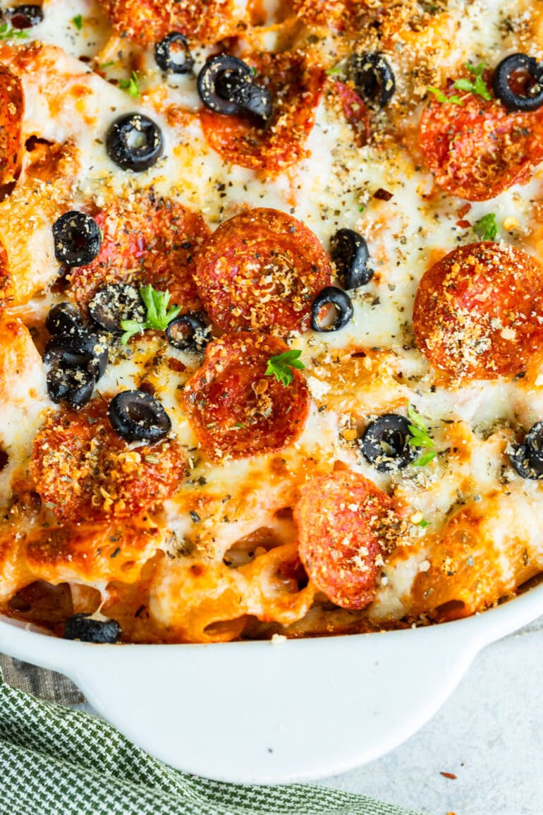 A photo of a roasted Italian pepper pizza casserole sprinkled with thinly sliced olives and fresh herbs