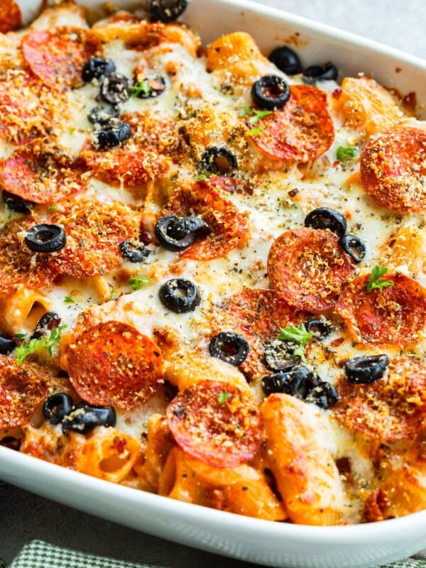 a photo of a cheesy pepperoni pasta casserole topped with sliced olives and melted cheese