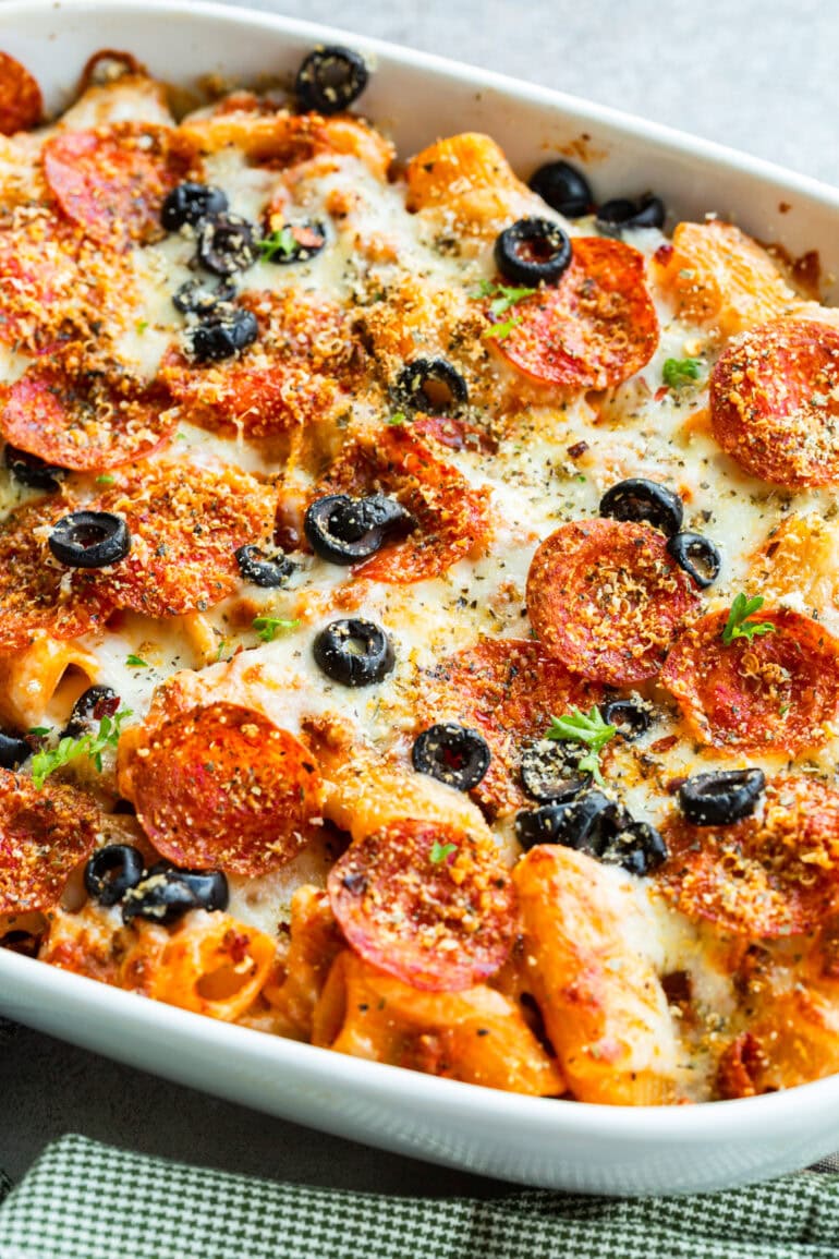 a photo of a cheesy pepperoni pasta casserole topped with sliced olives and melted cheese