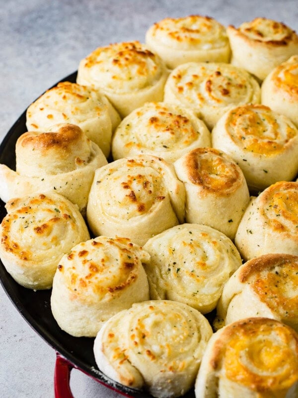 A pan full of cheese doodle garlic cheesy bread. The rolls are made like cinnamon rolls and baked to a golden brown.