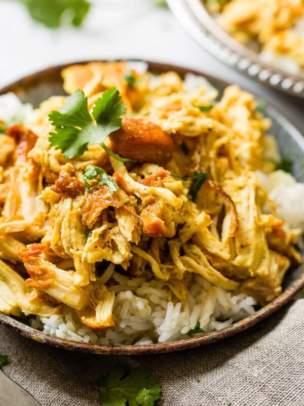 A metal, vintage bowl filled with white long grain rice and shredded chicken with a simple honey curry sauce made in an instant pot with cilantro on top. easy instant pot honey chicken