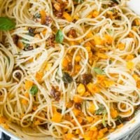 A photo of a large pot full of cooked spaghetti, chopped fresh basil, roasted butternut squash, cheese, and sun dried tomatoes.