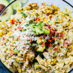 A close up photo of a bow tie pasta salad with avocados, peppers, grilled corn, cilantro, and cotija cheese making up an Elote Mexican Corn Pasta Salad