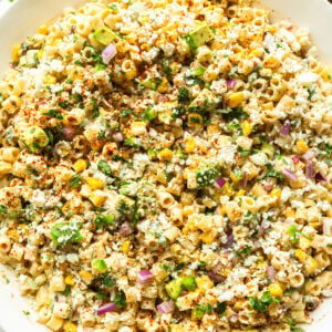 a bowl of creamy mexican street corn pasta salad with corn, cilantro, red onions, ditalini pasta and creamy dressing