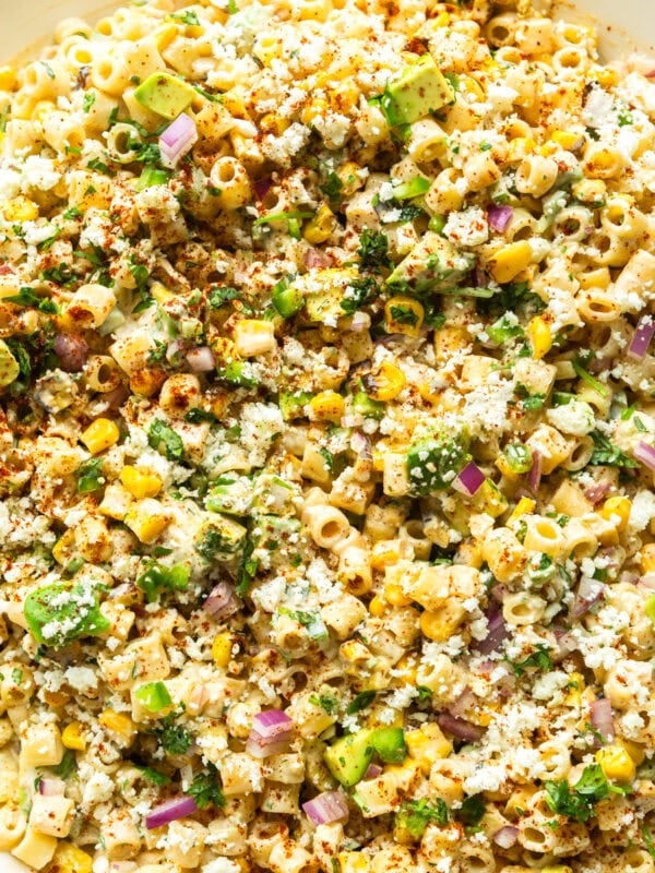 a bowl of creamy mexican street corn pasta salad with corn, cilantro, red onions, ditalini pasta and creamy dressing
