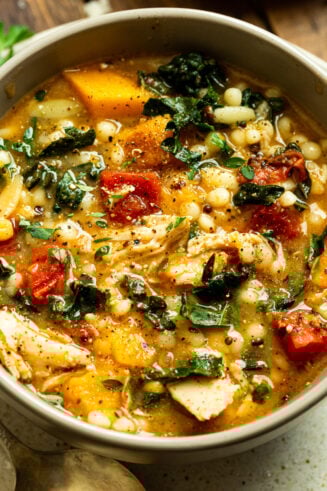 a photo of a bowl full of fall chicken stew including quinoa, chunks of butternut squash, chicken, and kale.
