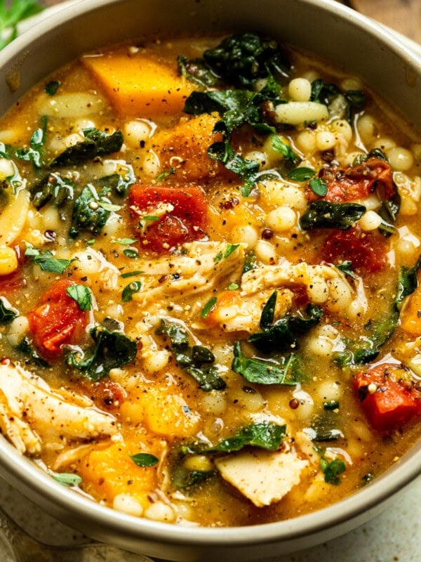 a photo of a bowl full of fall chicken stew including quinoa, chunks of butternut squash, chicken, and kale.