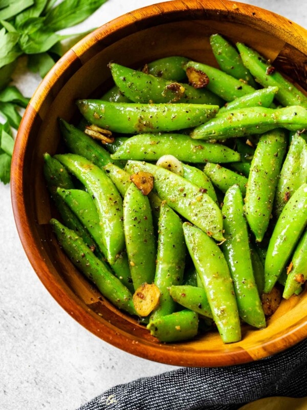 a wooden bowl with garlic sauted sugar snap peas