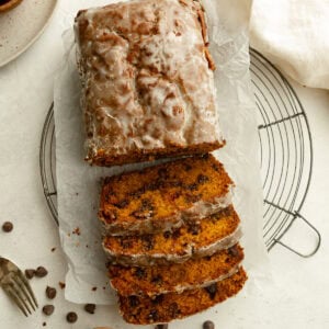 a loaf of glazed pumpkin bread with half of the loaf cut into slices