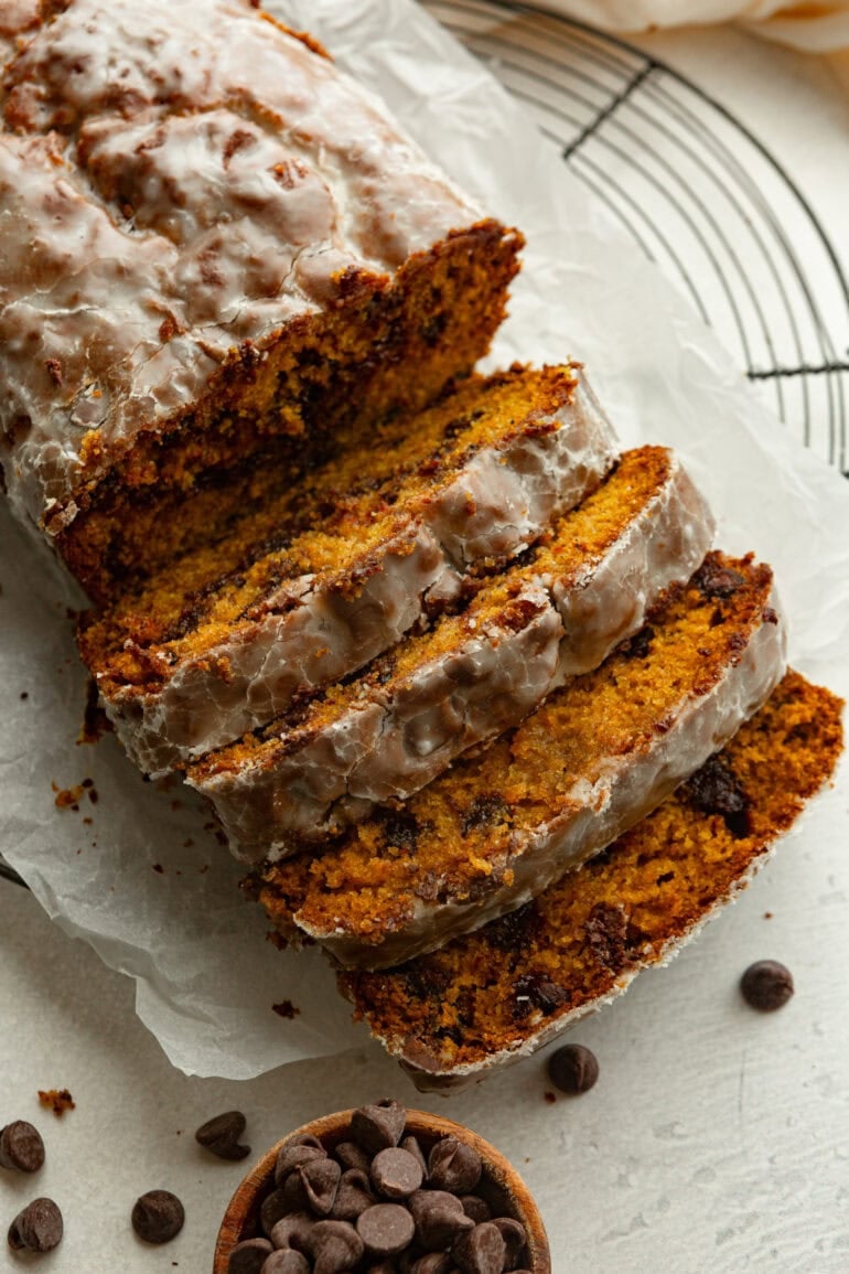 a loaf of pumpkin chocolate chip bread with several slices cut from the loaf laying next to the rest of the loaf