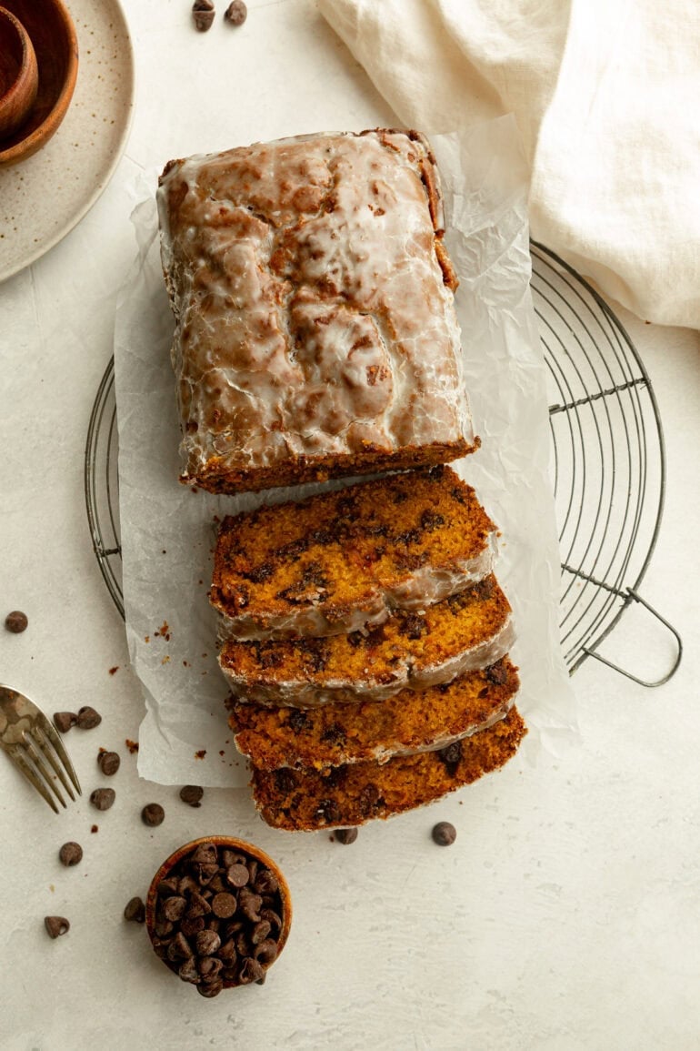 a loaf of glazed pumpkin bread with half of the loaf cut into slices