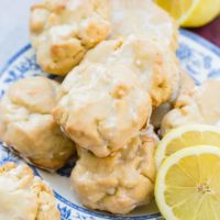 a pile of glazed lemon cookies on a blue floral vintage plate with slices of lemon