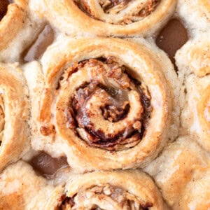 a photo taken over the top of a pan of golden baked apple cinnamon rolls topped with a sweet glaze
