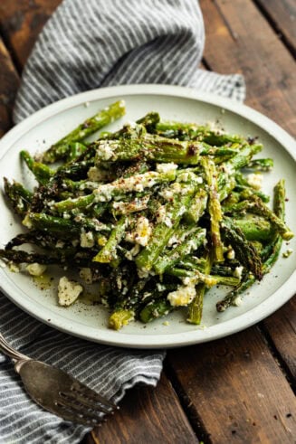 a photo of a white plate topped with a pile of grilled asparagus spears tossed with feta cheese