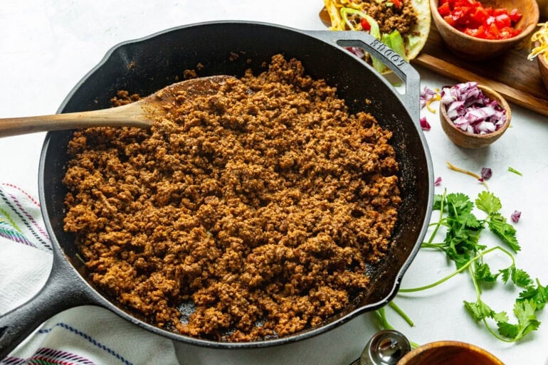 a cast iron skillet full of cooked seasoned ground beef ready for tacos