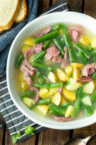a photo of a bowl of ham hock soup loaded with potatoes, green beans and chunks of ham