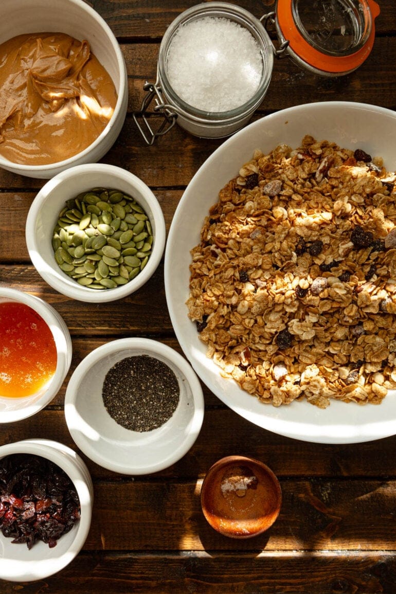 a photo of all the ingredients for healthy cereal bars in separate small bowls including oats, pepitas, honey, chia seeds