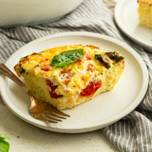 a serving of breakfast egg casserole loaded with cherry tomatoes, roasted red peppers and fresh basil