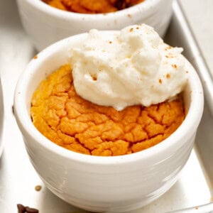 a photo of a pumpkin mug cake baked and topped with a dollop of whipped cream
