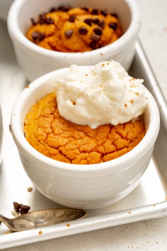 a photo of a pumpkin mug cake baked and topped with a dollop of whipped cream