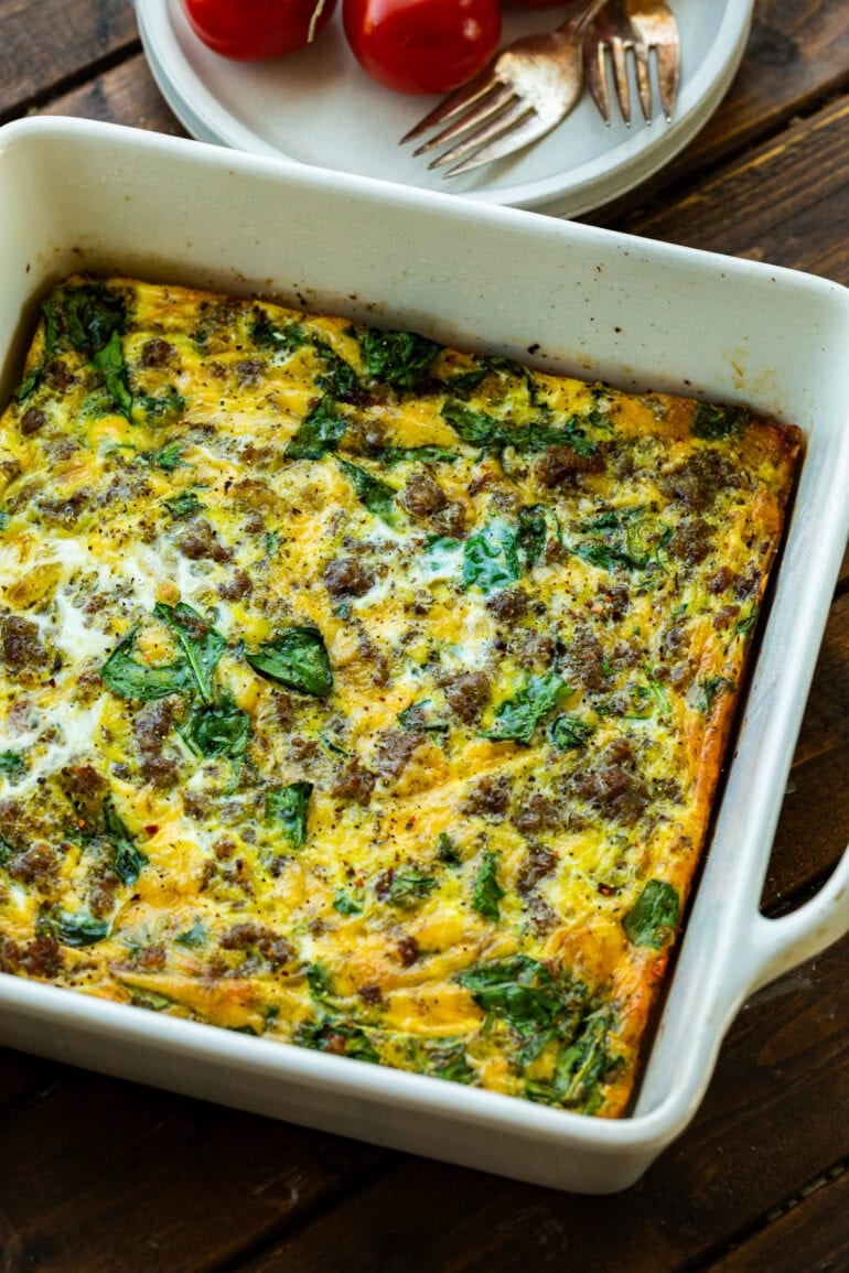 a square casserole dish of baked spinach and sausage egg casserole