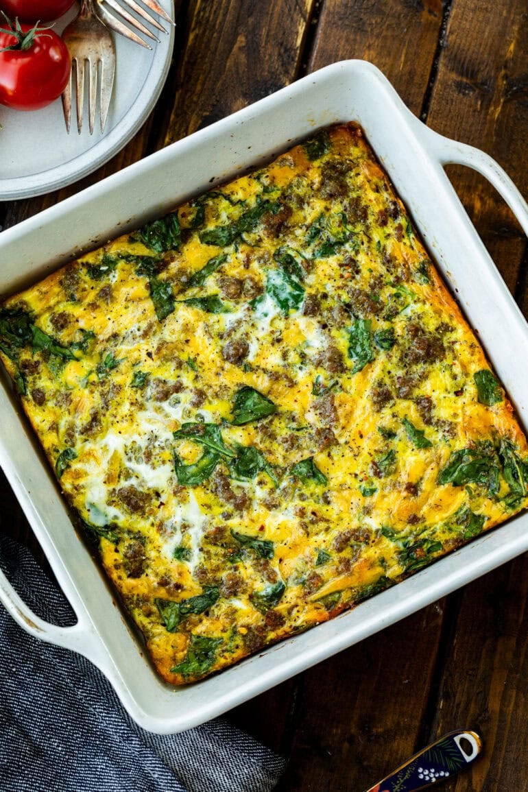 a baked spinach egg and sausage casserole in a square baking dish