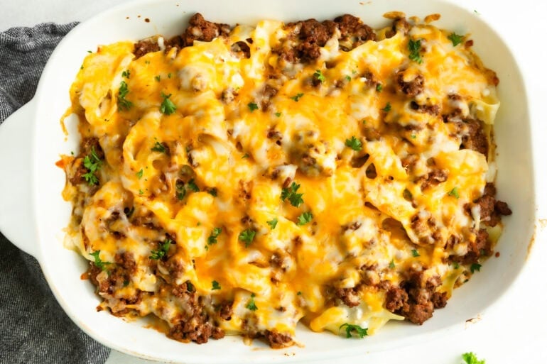 a cheesy ground beef noodle casserole in a casserole dish all topped with melted colby jack cheese