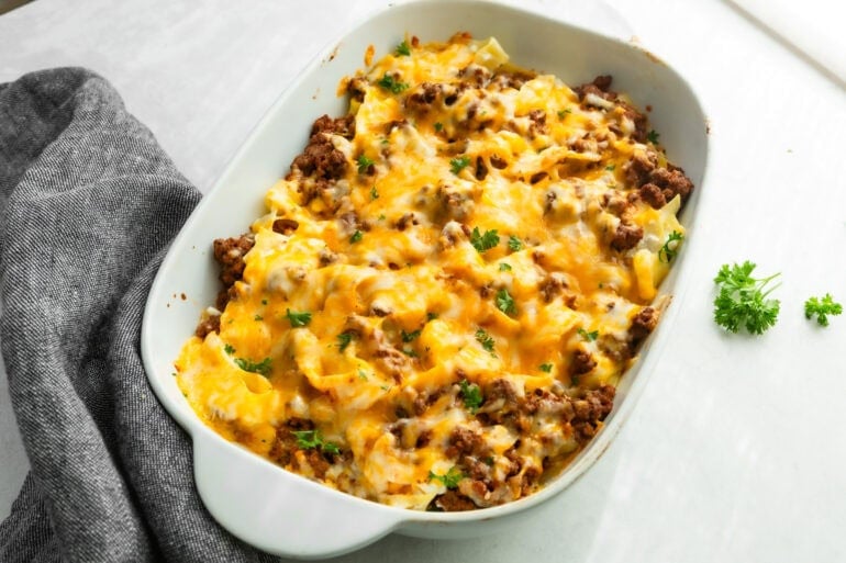 a large white casserole dish full of creamy ground beef noodle casserole topped with melted cheese