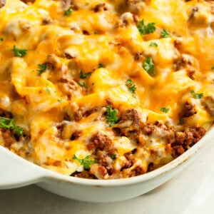 a large white casserole dish full of creamy ground beef noodle casserole topped with melted cheese