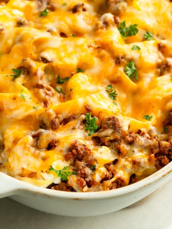 a large white casserole dish full of creamy ground beef noodle casserole topped with melted cheese