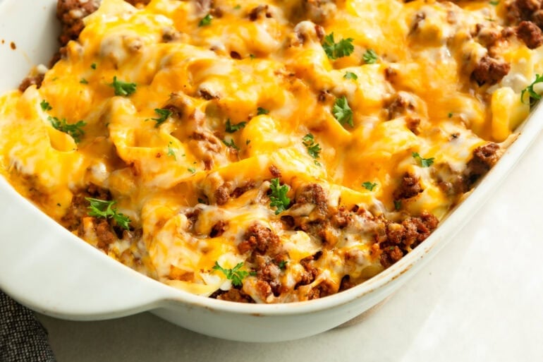 a large white casserole dish full of creamy ground beef noodle casserole topped with melted cheese