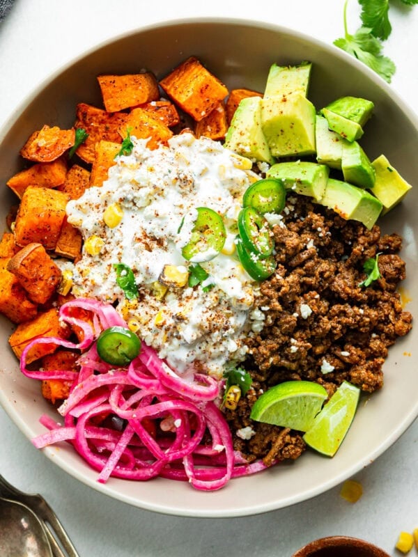a ground beef sweet potato bowl with elote street corn, avocado chunks and picked red onions