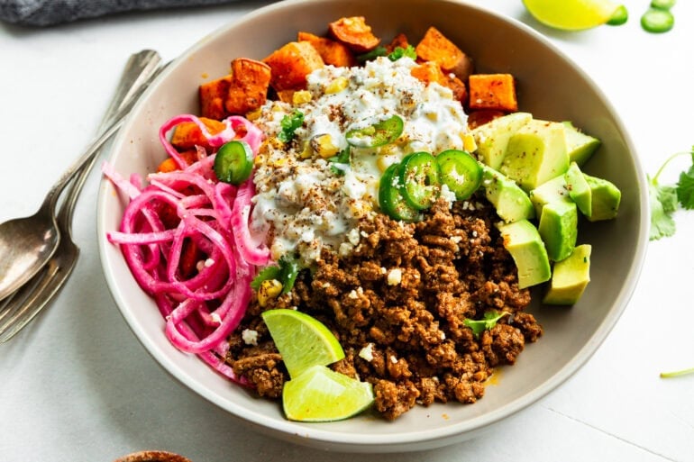 a ground beef sweet potato bowl with creamy elote, pickled red onions and avocado