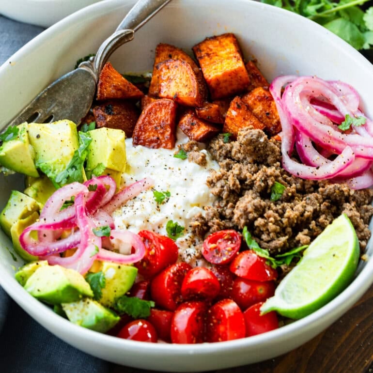 Photo of ground beef and sweet potato bowl topped with avocado, pickled red onions, mozzarella and cherry tomatoes