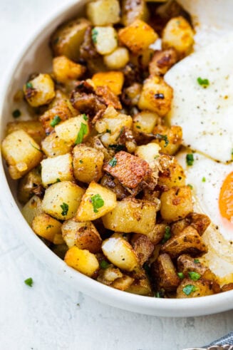 a photo of golden crispy home fries on a plate next to two fried eggs