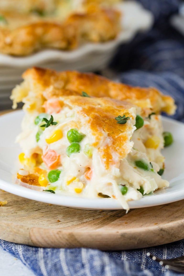 A close-up of a slice of chicken pot pie filled with chicken, carrots and peas.