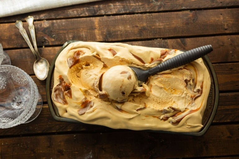 an ice cream scoop scooping up a serving of dulce de leche ice cream