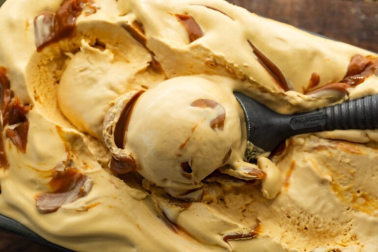 an ice cream scoop scooping up a serving of dulce de leche ice cream