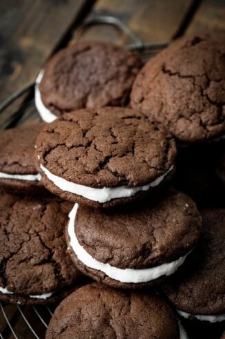 a photo of several homemade oreo cookies piled on each other sitting on a circular wire cooling rack