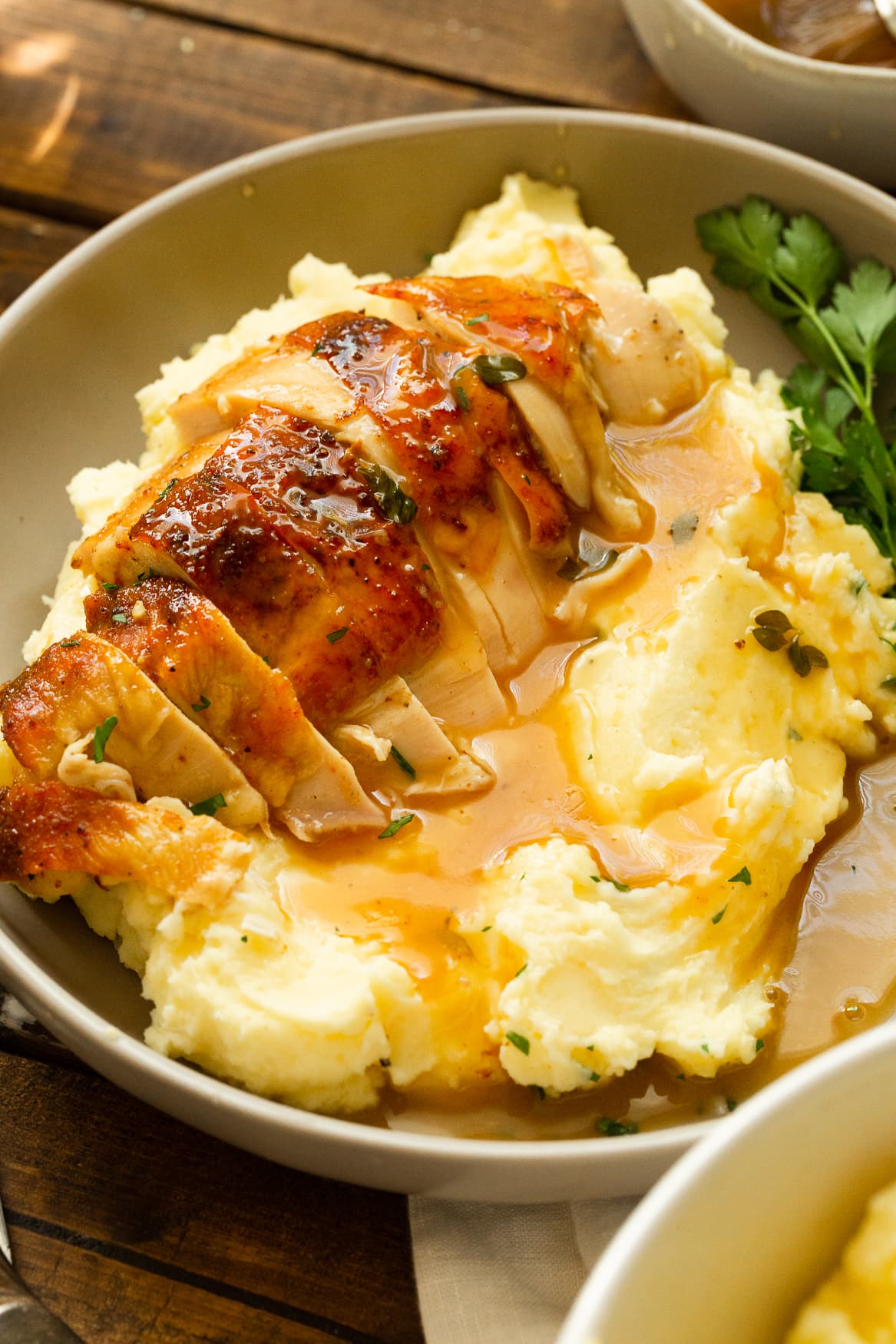 a photo of a serving of creamy mashed potatoes topped with gravy and golden roasted chicken breast that has been sliced